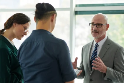 Business consultant explaining a strategy to two colleagues during a professional meeting in a modern office environment.