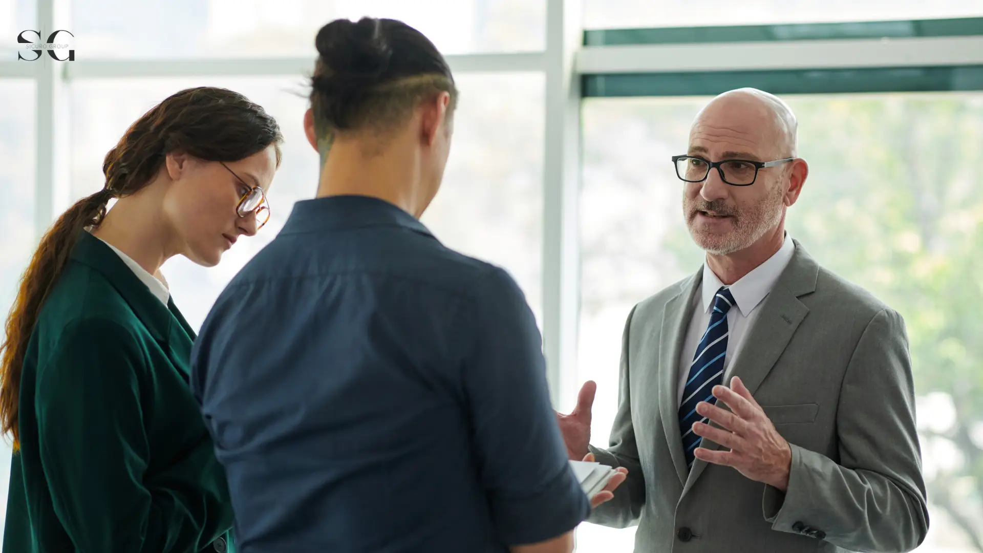 Business consultant explaining a strategy to two colleagues during a professional meeting in a modern office environment.