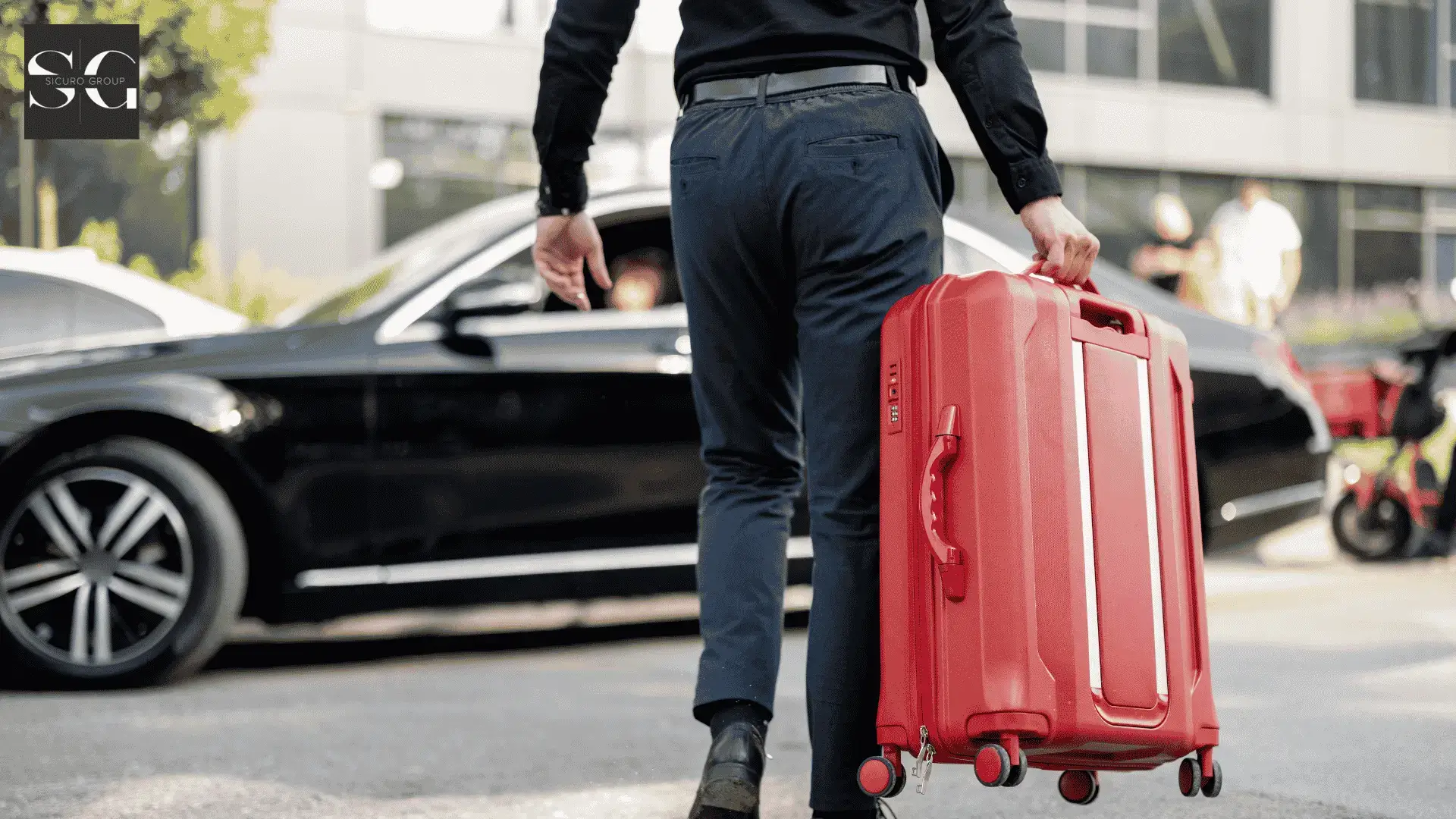 Business traveler with a red suitcase approaching a luxury sedan outside a modern building entrance.
