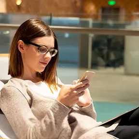 Woman using a smartphone while seated in a modern office lounge.