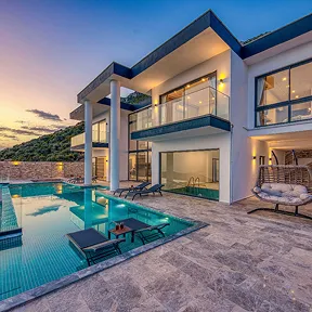 A modern luxury villa features an infinity pool, glass balconies, sleek architecture, and breathtaking sunset views.