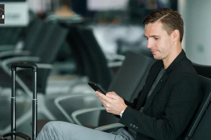 A business man with a suitcase in the airport checking their phone