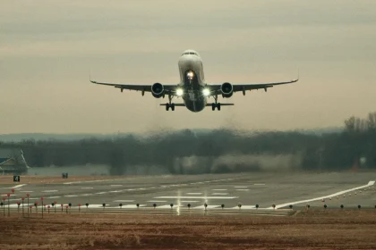An airplane approaching the runway for landing at an airport during hazy weather, with landing lights on and runway lights visible.